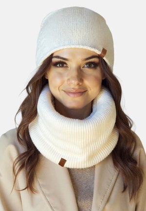 Bonnets et cols en tricot blanc, avec une texture rainurée et une étiquette en cuir. Design doux et chaud, adapté pour les temps froids.
