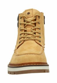 Stivale in suede beige con lacci beige, dotato di occhielli metallici e una suola robusta, visto frontalmente, evidenziando il suo design e la sua struttura.