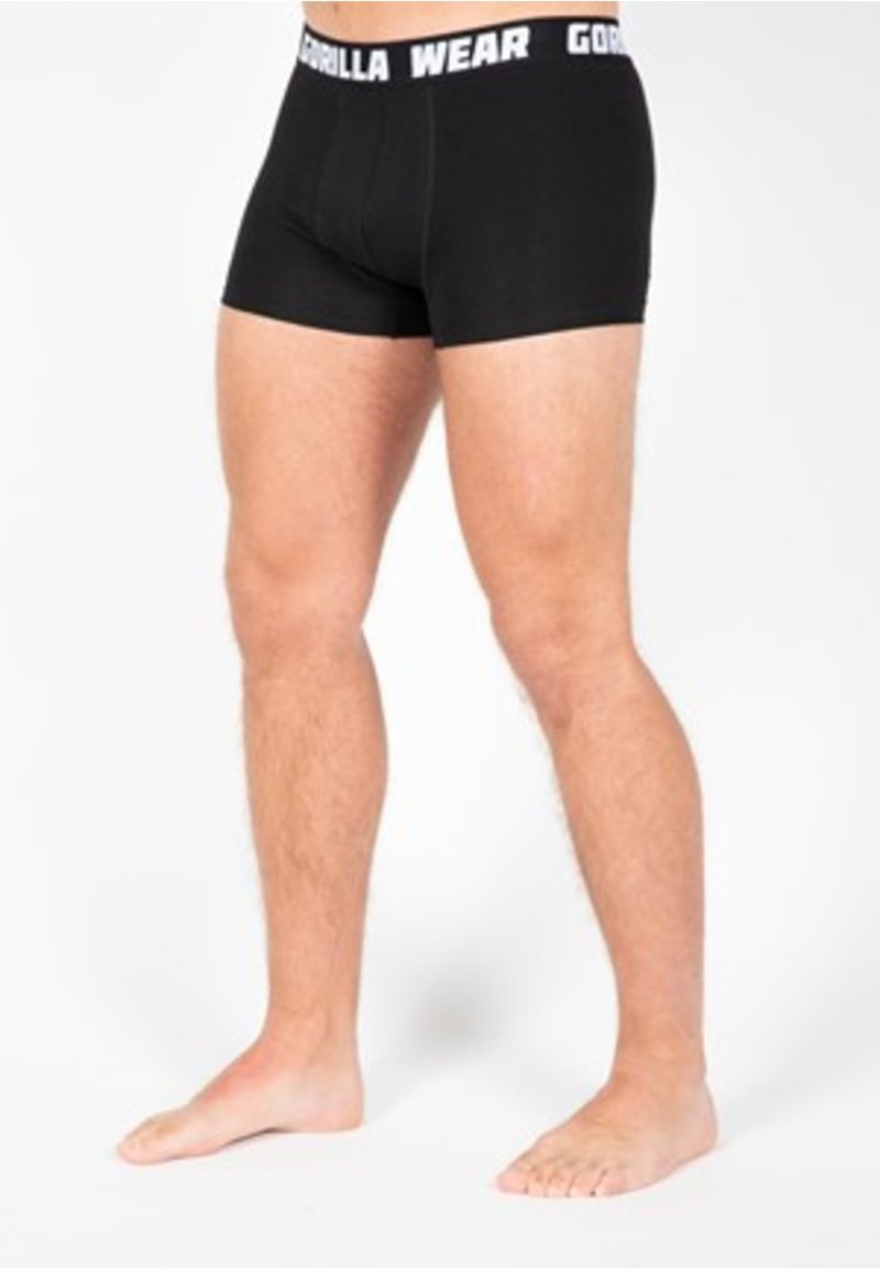 Zwarte boxer shorts van rekbare stof, met een witte merkband in de taille en een aansluitende pasvorm. Soepele textuur zonder patronen of accenten.