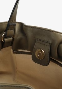 Sac à main en cuir vert olive avec une finition texturée, doté d'une fermeture à bouton pression doré, d'une poche intérieure et de coutures décoratives.