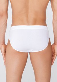 Caleçons blancs pour hommes en tissu lisse et extensible. Ils présentent une ceinture élastique douce, une coupe ajustée et des coutures minimales pour un confort optimal.