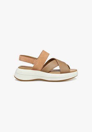 Sandali in pelle color cuoio con design a doppia fascia incrociata, cinturino posteriore regolabile e suola bianca testurizzata. Plantare leggermente imbottito.