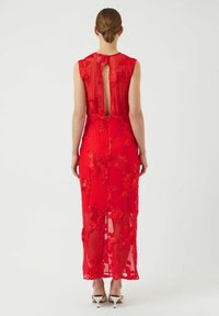 Rød maxikjole laget av gjennomsiktig stoff med blomsterbroderi. Har en åpning med nøkkelhull bak og er stylet med hælsandaler.