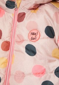 Doudoune rose avec de grands pois multicolores en rose, jaune, marron et bleu marine. Comprend un badge circulaire "Hey ! Girl".