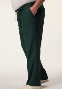 Pantaloni larghi di colore verde scuro realizzati in materiale leggero, con vita regolabile tramite cordoncino, tasche laterali e design a gamba dritta.