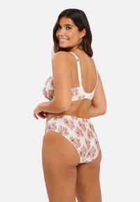 Ensemble de bikini floral avec une base blanche, orné de fleurs roses et orange. Le haut a des bretelles ajustables et le bas est taille haute avec une finition texturée.