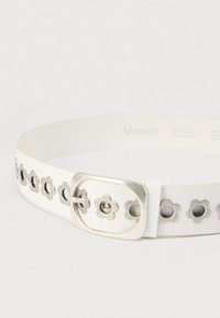 Λευκή δερμάτινη ζώνη με ασημένιες κοπές σε σχήμα λουλουδιού και ορθογώνια μεταλλική αγκράφα. Ομαλή υφή με μινιμαλιστικό σχέδιο.