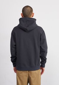 Felpa con cappuccio grigia scura, dotata di un cappuccio ampio, polsini e orlo a costine. Tessuto liscio, taglio casual e design minimalista. Nessun logo o motivo visibile.