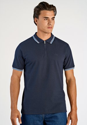 Marinblå polo med dragkedja i kragen, med ljusblå ränder på kragen och ärmarna, tillverkad av ett mjukt, elastiskt material.