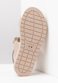 Sandalia beige con suela de goma texturizada, que cuenta con correas ajustables, logotipo de marca y detalles de artesanía italiana. Talla 37.