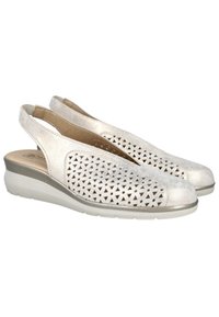 Zapatos slingback en cuero metálico plateado claro con patrones geométricos cortados, punta redondeada y suela de cuña blanca acolchada.
