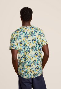 Korte mouwen shirt in lichtgroen met een bloemmotief met blauwe en gele accenten. Gemaakt van zachte stof met een ontspannen pasvorm.
