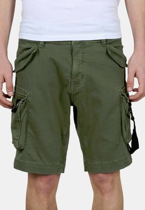 Mann trägt olivgrüne Cargoshorts mit mehreren Klappentaschen und schwarzen Riemendetails, kombiniert mit einem weißen Hemd.