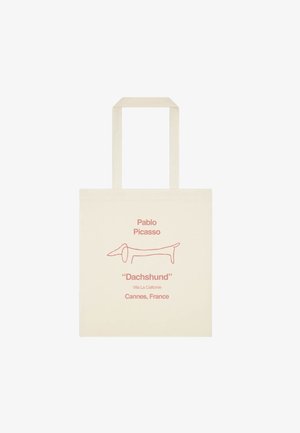 Beżowa torba na ramię z długimi uchwytami, z prostym czerwonym konturem przedstawiającym jamnika oraz tekstem odnoszącym się do Pablo Picassa i Cannes, Francja.