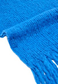 Jasnoniebieski dziergany szalik o teksturowanym wzorze i frędzlach na końcach, wykonany z miękkiego, puszystego materiału.