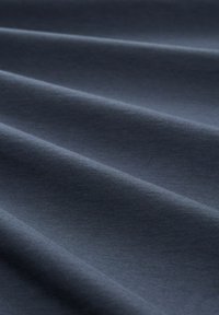 Donker marineblauwe stof met een gladde textuur, kenmerkt zich door subtiele golfpatronen, wat de lichtgewicht en rekbare eigenschappen benadrukt. Minimaal patroon en ontwerp.