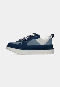 Tengerészkék és világoskék sneaker velúr és hálós anyagból, fehér fűzőkkel, párnázott nyakkal és vastag fehér talppal. UGG logó a sarokon.