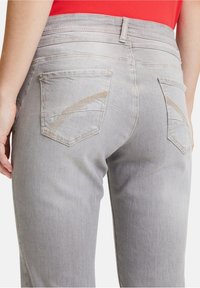 Grå denimjeans med slim fit, med bakfickor som har ett dekorativt sydd mönster och en något blekt textur.