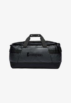 Bolsa de lona negra con acabado brillante, que cuenta con dos asas superiores, un bolsillo frontal con cremallera y un detalle de logotipo en el lateral. Base texturizada.