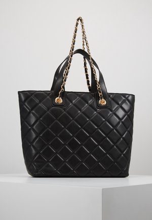 Sorte quiltede totebag lavet af læder, med en kæde-rem og to korte håndtag med guldfarvede detaljer. Firkantet form og glat tekstur.