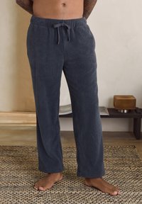 Dark gray, ribbed lounge pants made of soft fabric, featuring an elastic waistband with a drawstring. Straight-leg design, unhemmed cuff edges.