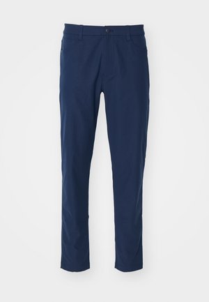 Pantaloni bleumarin cu o textură netedă, croi slim, buzunare frontale și închidere cu un singur nasture la talie. Fără modele vizibile.