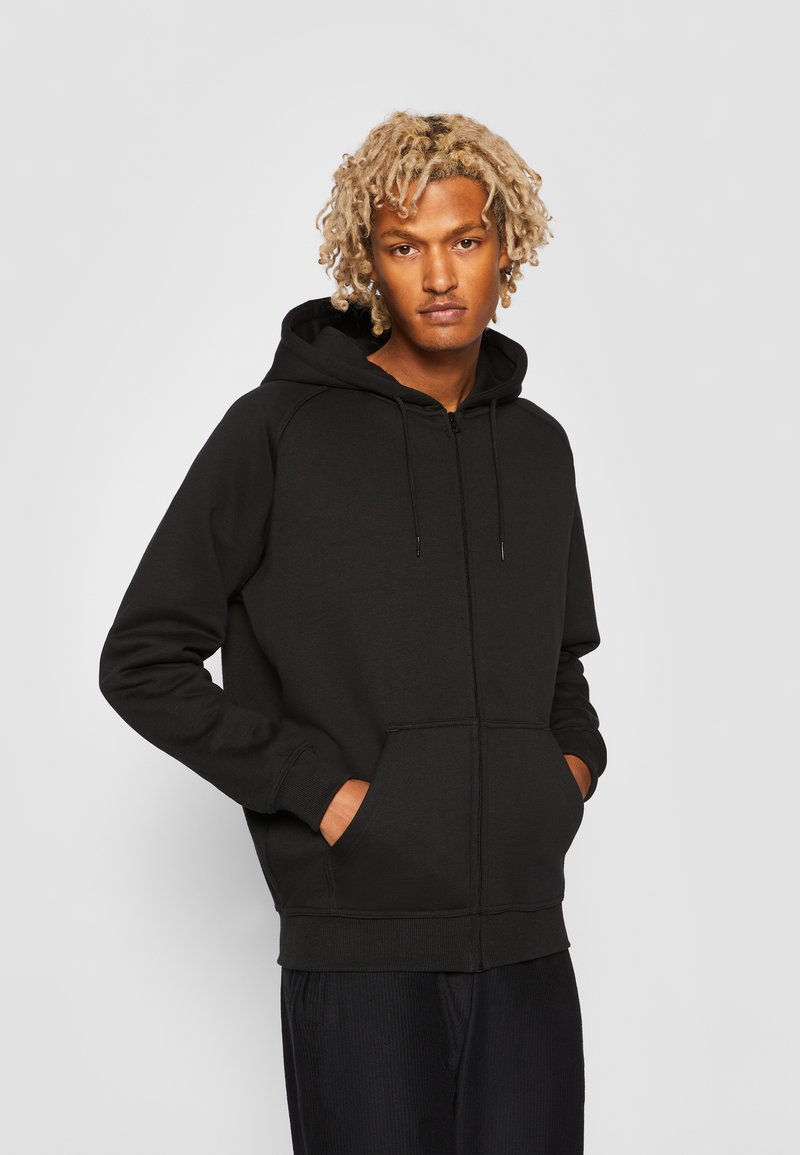 Sort zip-up hoodie lavet af blanding af bomuldsstof. Har en hætte med snoretræk, ribbet manchetter og to sidelommer. Simpelt, udekoreret design.