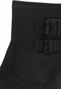 Bottine en cuir noir avec un bout arrondi, deux sangles horizontales avec boucles et un dessus texturé. Coutures sur les côtés.