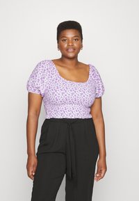Top com estampa floral roxa, com mangas curtas em forma de puff, decote quadrado e cintura pregueada. Combinado com calças pretas de cintura alta com detalhe de laço.