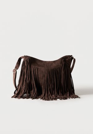 Mørkebrun semsket crossbody-veske med lange frynser og justerbar skulderstropp mot lys bakgrunn.