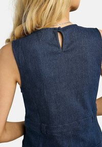 Rochie din denim cu croială mulată și fără mâneci. Culoare albastru închis, cu o deschidere tip cheie la spate și detaliu cu centură în talie.