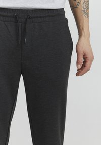Dark gray sweatpants with an elastic waistband, drawstring closure, and side pockets. Made from a soft, textured fabric.