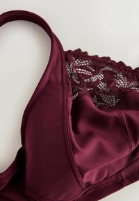 Burgundy rinnah, mille servade detailide ja sileda kangaga, reguleeritavad rihmad ja õmblusteta tassid.