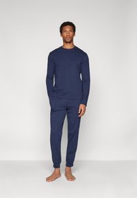 Navy blue cotton loungewear set with long sleeves and elastic waist pants, featuring a simple design and smooth texture. No patterns or accents.