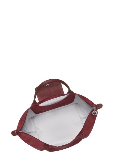 Burgundy leather tote bag with dual handles and a zip closure. Features a smooth, spacious interior lined in white fabric with side pockets.