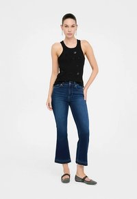 Top negru fără mâneci cu ornamente, asortat cu blugi evazați albaștri și pantofi platați gri. Culori solide și design simplu.