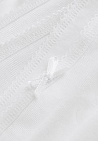Witte stof met delicate kanten randen en een klein satijnen strikdetail. De textuur is glad met een lichte glans.