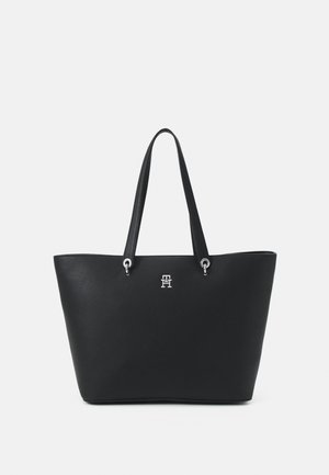 Bolso tote de cuero negro con superficie texturizada, herrajes en plata y asas dobles. Presenta acento de logo en la parte frontal y diseño de apertura superior.