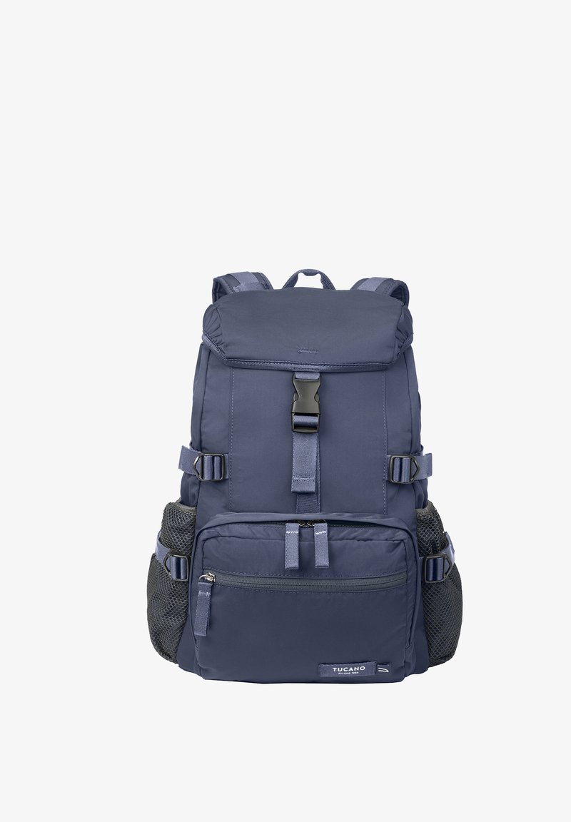 Zaino blu navy con patta superiore e fibbia, tasca frontale con cerniera, spallacci laterali regolabili e portabottiglie in rete su entrambi i lati.