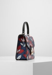 Námořnická kabelka s květinovým vzorem v červené a bílé, černý popruh, zlaté kovové doplňky, obdélníkový tvar, hladká textura a klopové zavírání.