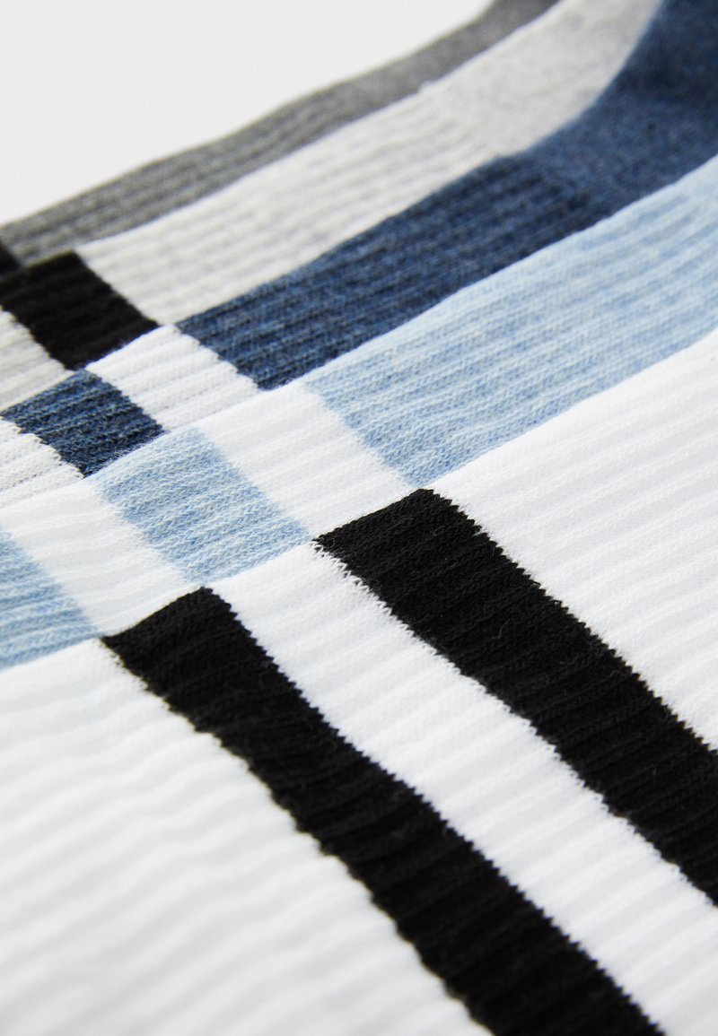 Textil a rayas que presenta colores alternos de blanco, negro, azul oscuro, azul claro y gris, con una textura acanalada y un patrón horizontal.