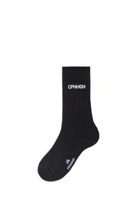 Mustaläbised, millel on valge tekst "CPNHGN." Mugavuseks loodud, kinnitatud varba ja sileda tekstuuriga.