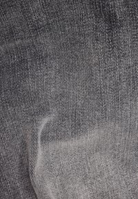 Černá a šedá texturovaná tkanina se vzorovaným pletením, s jemným gradientním efektem. Materiál vypadá měkký a mírně elastický.