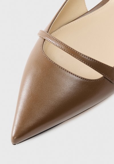 Ruskea nahkainen kärkiosastaan terävä kenkä, jossa on sileä pinta, koristeellinen remmi jalkapöydän yli ja hillitty, neutraali sisäpuoli.