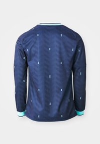 Granatowa koszula z długim rękawem w wzór jodełki i drobnymi jasnoniebieskimi geometrycznymi kropkami, z mankietami i kołnierzem w paski w kolorze aqua i białym.