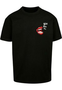 Camiseta de algodón negra con un gráfico de una boca abierta con labios rojos y texto blanco que dice "Bla Bla Bla" impreso en el lado izquierdo. De mangas cortas.