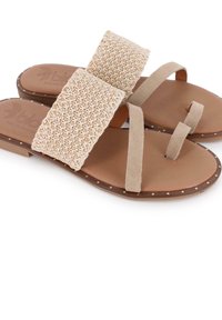 Sandalias beige con correas de tela trenzada, detalles de ante suave, suela plana y costuras decorativas a lo largo del borde. Ideales para un uso informal.