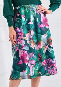 Jupe florale en vert foncé avec de grandes fleurs roses, blanches et vertes. Fabriquée en tissu lisse, elle possède une taille ajustée et une coupe au genou.