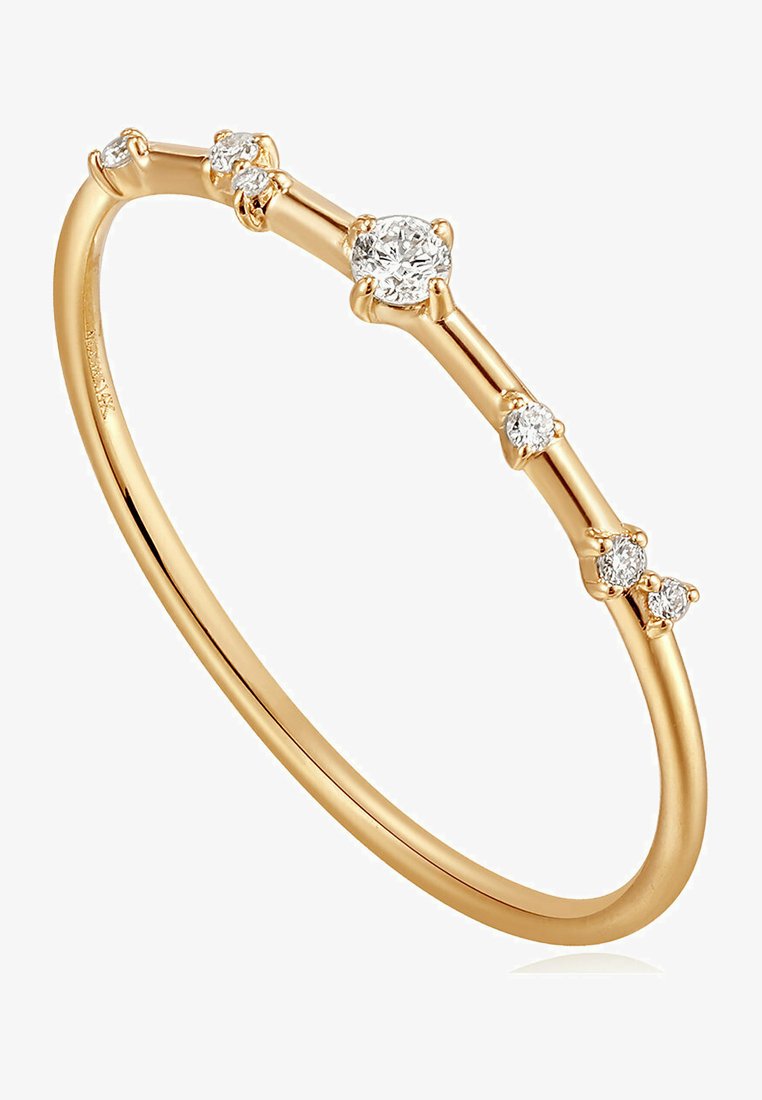 Bague en or avec un design fin et élégant, ornée de cinq diamants ronds de tailles variées dispersés le long de l'anneau.