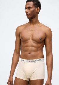 Μπεζ βαμβακερές μποξερές με μαλακή υφή, που διαθέτουν λαστιχένια ζώνη με λογότυπο σε λευκό χρώμα με κόκκινες και μπλε λεπτομέρειες.